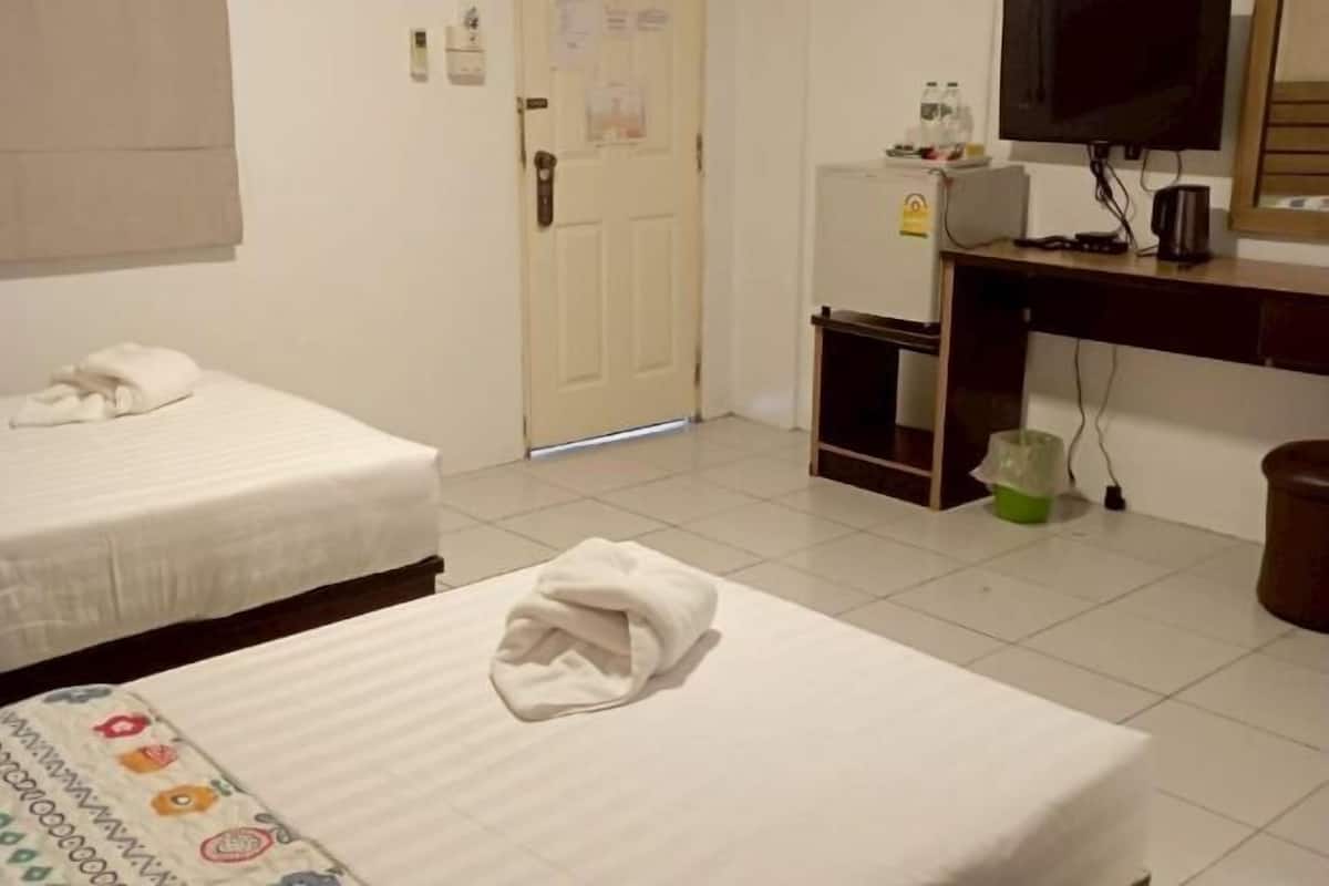 A hotel room with two beds, a television, a desk with a computer, and a trash bin.