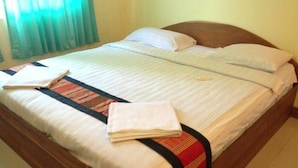 A neatly made bed with a striped bedspread, pillows, and folded towels. - Lankham Hotel (Pakse)