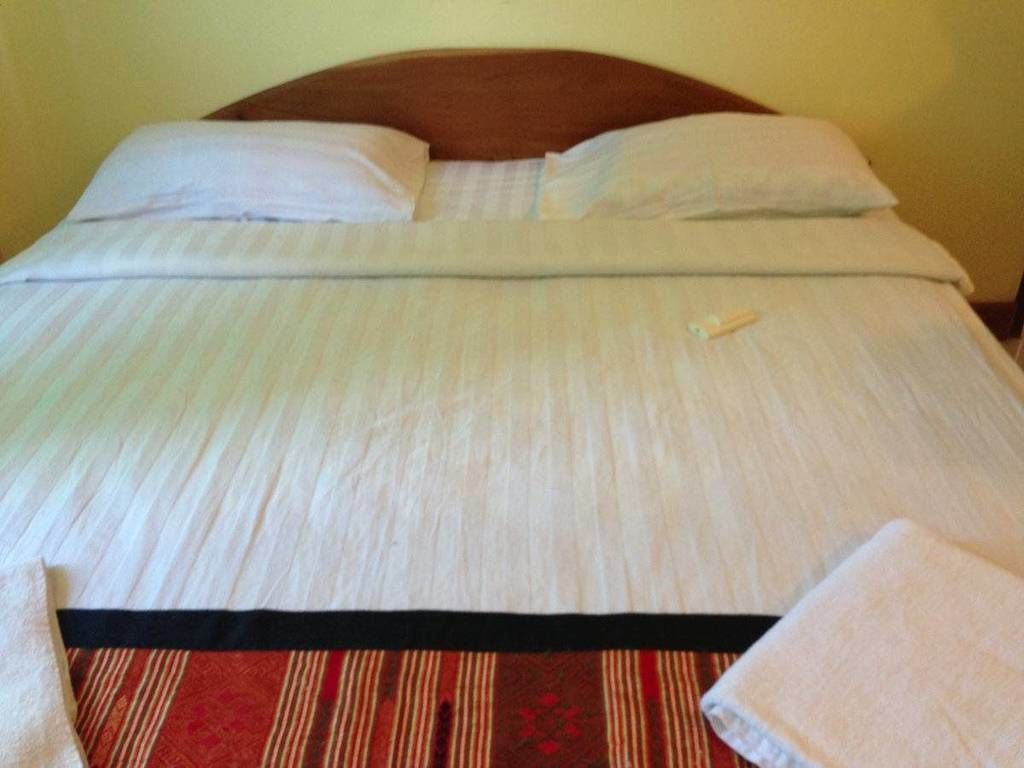 Una cama bien hecha con una colcha a rayas, almohadas y una toalla doblada al lado.