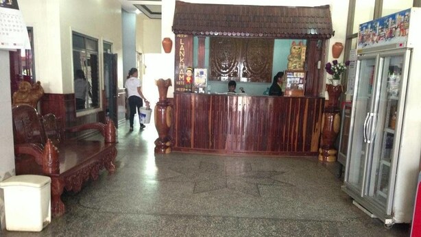 A reception area with a wooden counter, a refrigerator, and a seating area with chairs. - Lankham Hotel (Pakse)