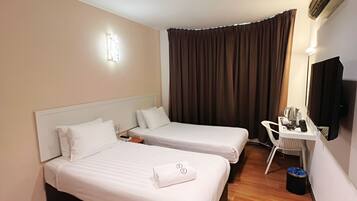 Une chambre d’hôtel avec deux lits, un bureau, une chaise, une télévision et un climatiseur fixé au plafond.
