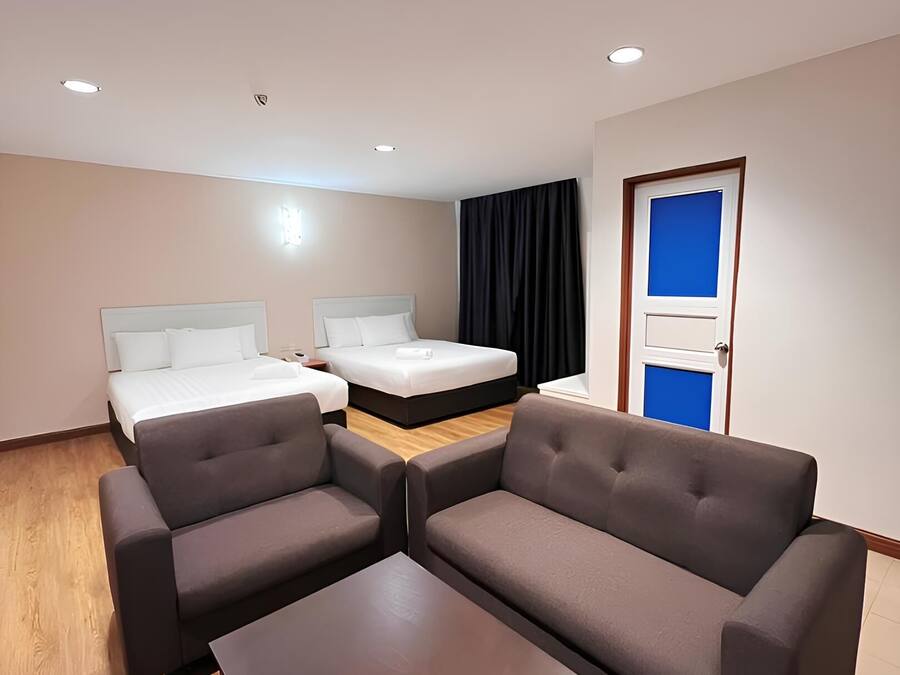 A modern hotel room with two beds, a sofa set, and a small table.
