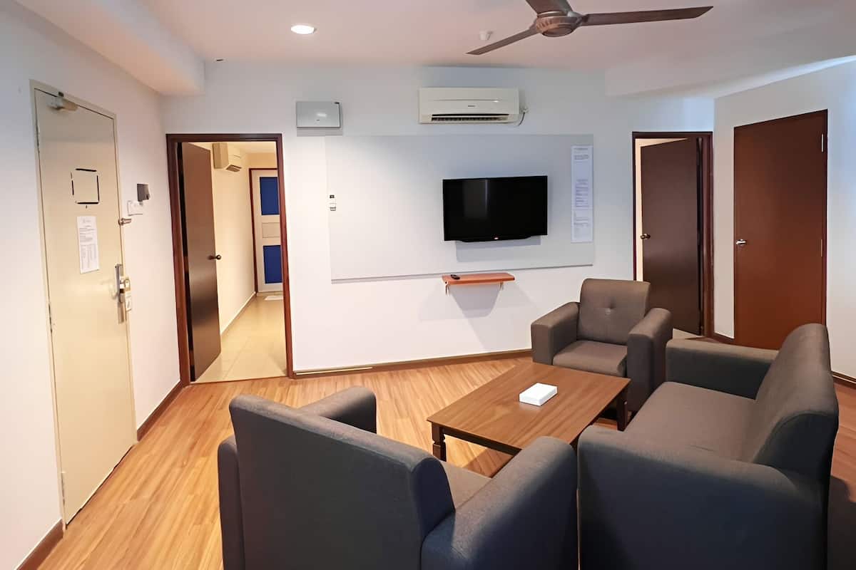 A modern hotel room with a flat-screen TV mounted on the wall, a ceiling fan, and a wooden coffee table.