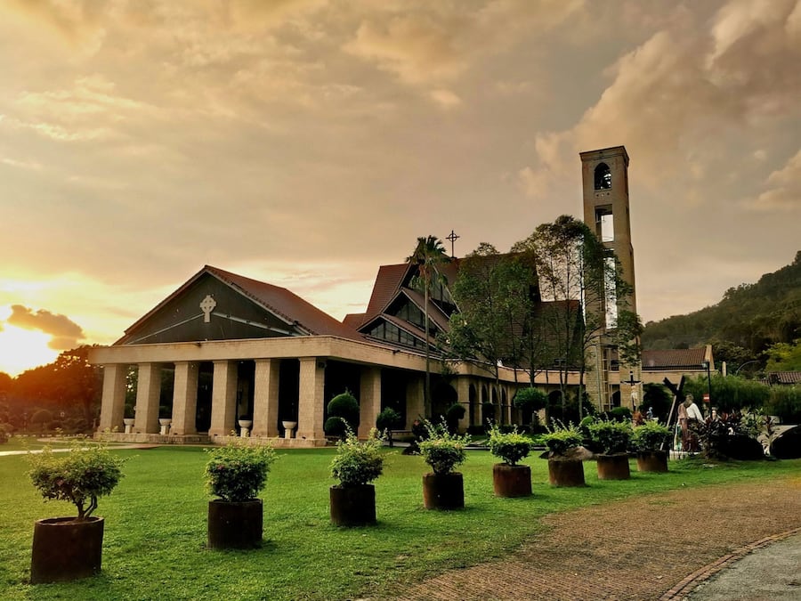 A historic building with a prominent tower and columns, surrounded by a well-maintained lawn and potted plants.