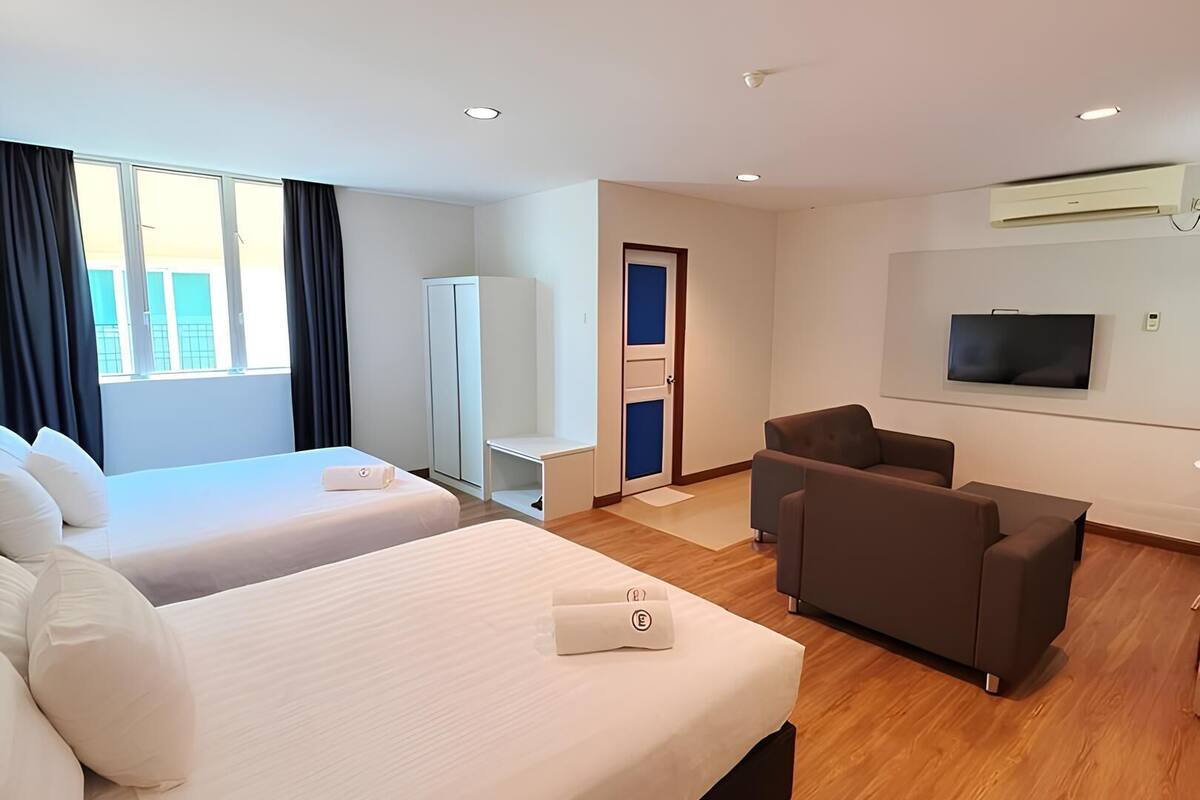 A hotel room with two beds, a sofa, a TV, and a wardrobe.