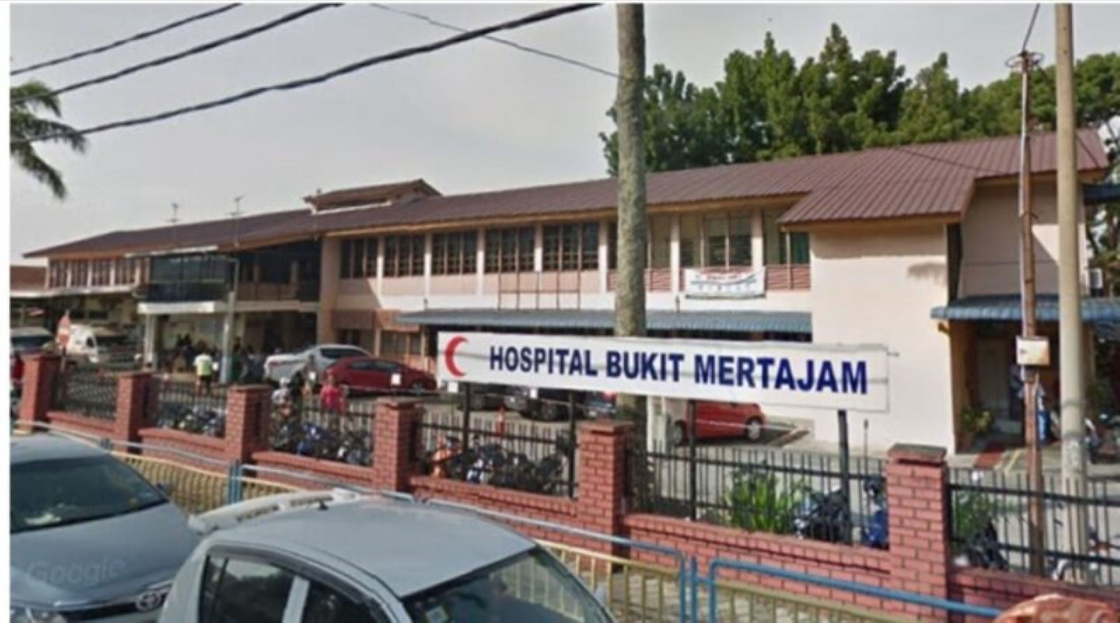 Um edifício de hospital com uma placa indicando "HOSPITAL BUKIT MERTAJAM".