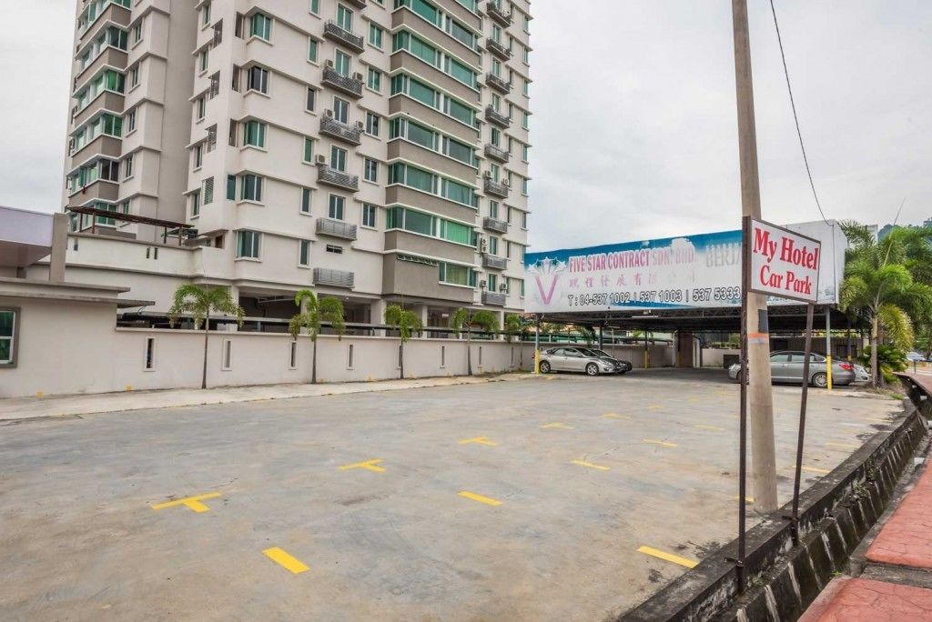 Un hotel de varios pisos con un estacionamiento frente a él.