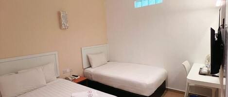 Habitación de hotel con dos camas, un escritorio, una silla, un ventanal pequeño y una lámpara en el techo.