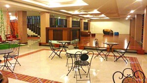 A spacious lobby with multiple seating areas, including tables and chairs, and a staircase leading to an upper level. - Le Luxe Residence (Udon Thani)