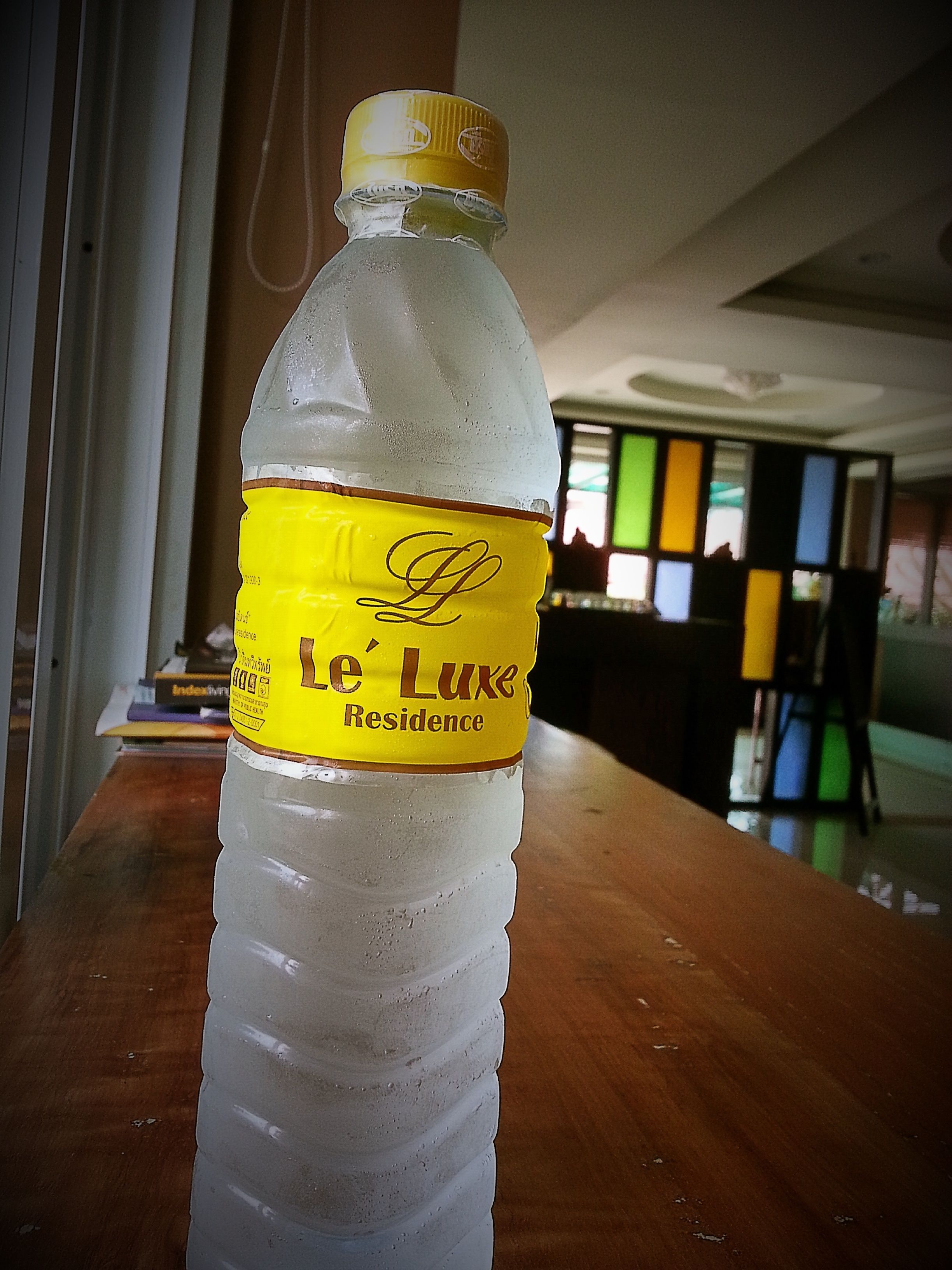 Eine Flasche Wasser des Le Luxe Residence auf einer Holztisch.