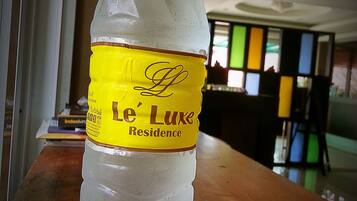 Eine Flasche Wasser des Le Luxe Residence auf einer Holztisch.