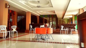 A spacious lobby with a high ceiling, a central seating area with orange chairs, and a clock on the wall. - Le Luxe Residence (Udon Thani)