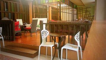 A dining area with white chairs, a wooden table, and a staircase with a railing.