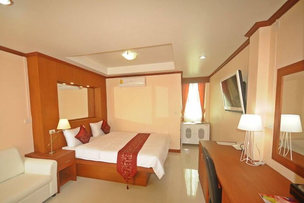 A hotel room with a bed, a desk, a chair, a TV, and a window with curtains.