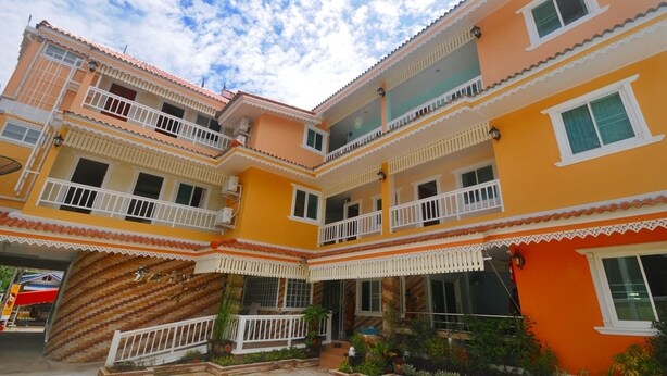 Un edificio de varios pisos con balcones, una escalera y un pequeño jardín.