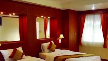 A hotel room with two beds, a large mirror, and red curtains.