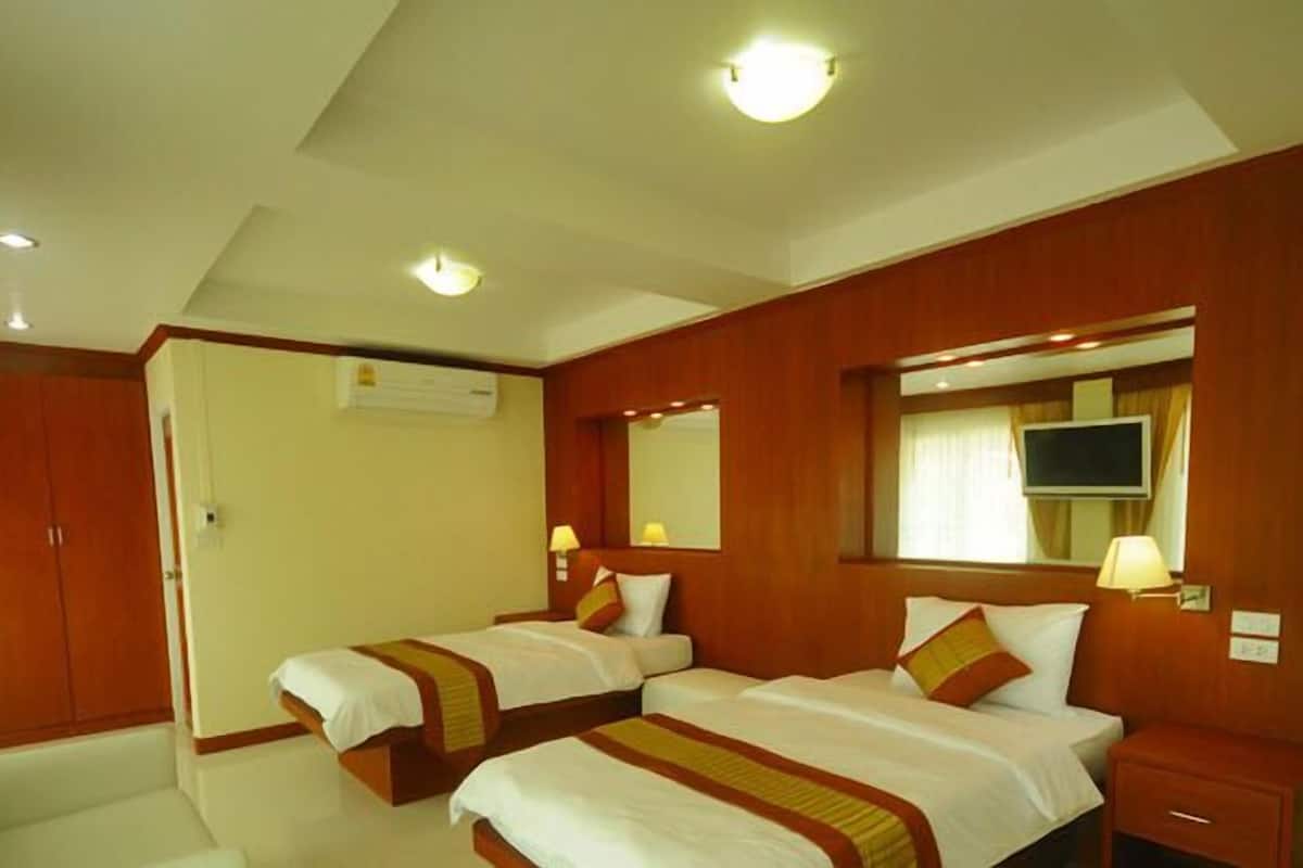 A hotel room with two beds, a wooden wardrobe, a TV, and a mirror.