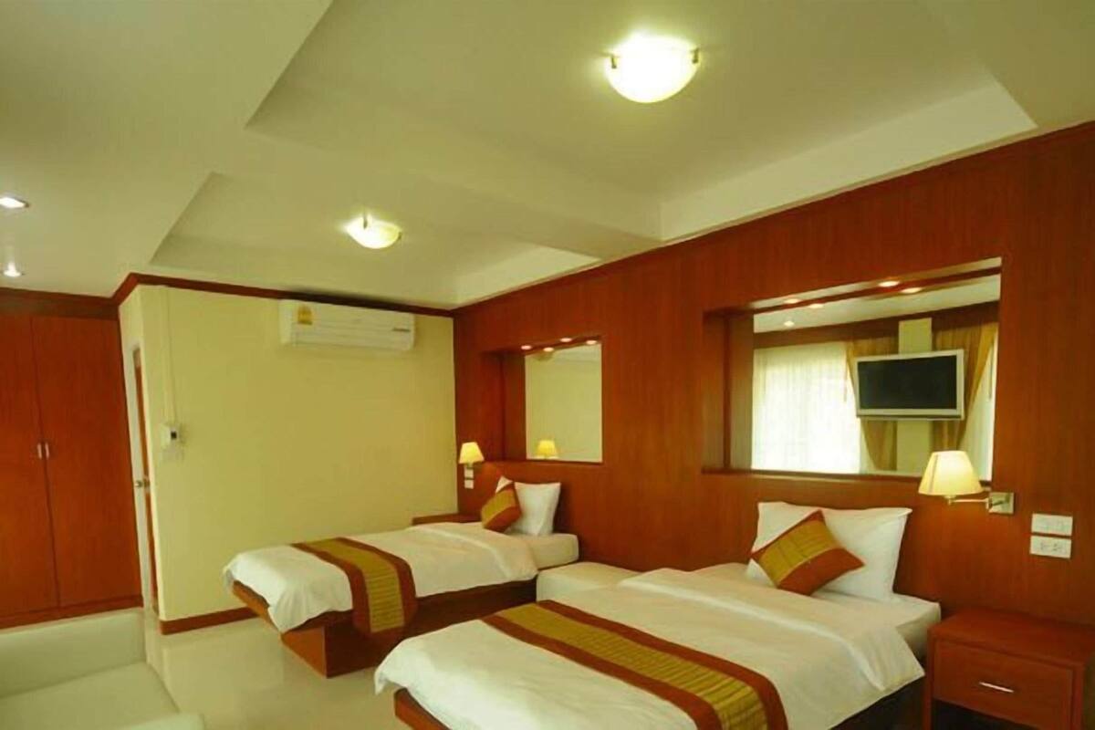 A hotel room with two beds, a TV, a mirror, and a wardrobe.