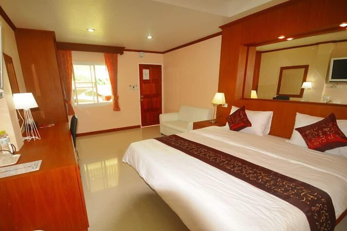A hotel room with a bed, a desk, a chair, a TV, and a door.