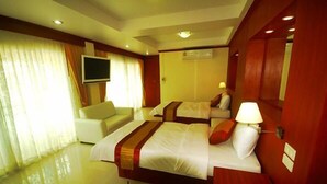 Una habitación de hotel con dos camas, un televisor, un sofá y una lámpara.