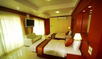 Una habitación de hotel con dos camas, un televisor, un sofá y una lámpara.