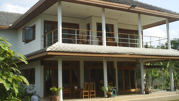 A two-story house with a balcony, large windows, and potted plants. - Ban Rim Nam Riverside Resort (Nan)