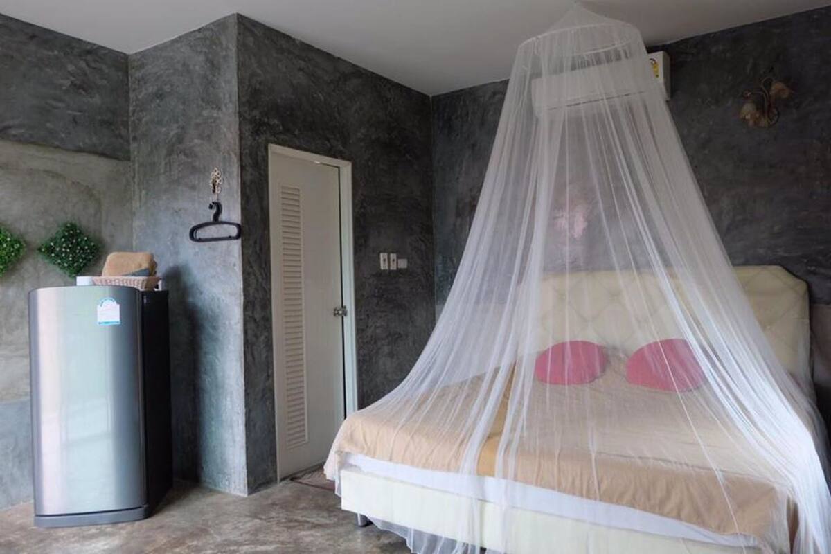 A bedroom with a bed under a mosquito net, a door, and a small heater.