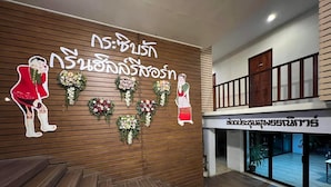 A reception area with a wooden wall, floral arrangements, and a sign in a foreign language. - Green Hill Resort (Pua)