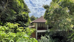 A two-story house surrounded by dense greenery, with a balcony on the upper floor. - Green Hill Resort (Pua)