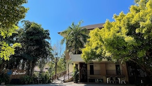 A building with a staircase leading to a balcony, surrounded by lush greenery and trees. - Green Hill Resort (Pua)