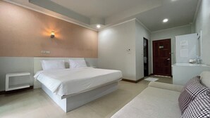 A modern hotel room with a large bed, a bedside table, a wardrobe, and a bathroom visible through an open door. - Green Hill Resort (Pua)