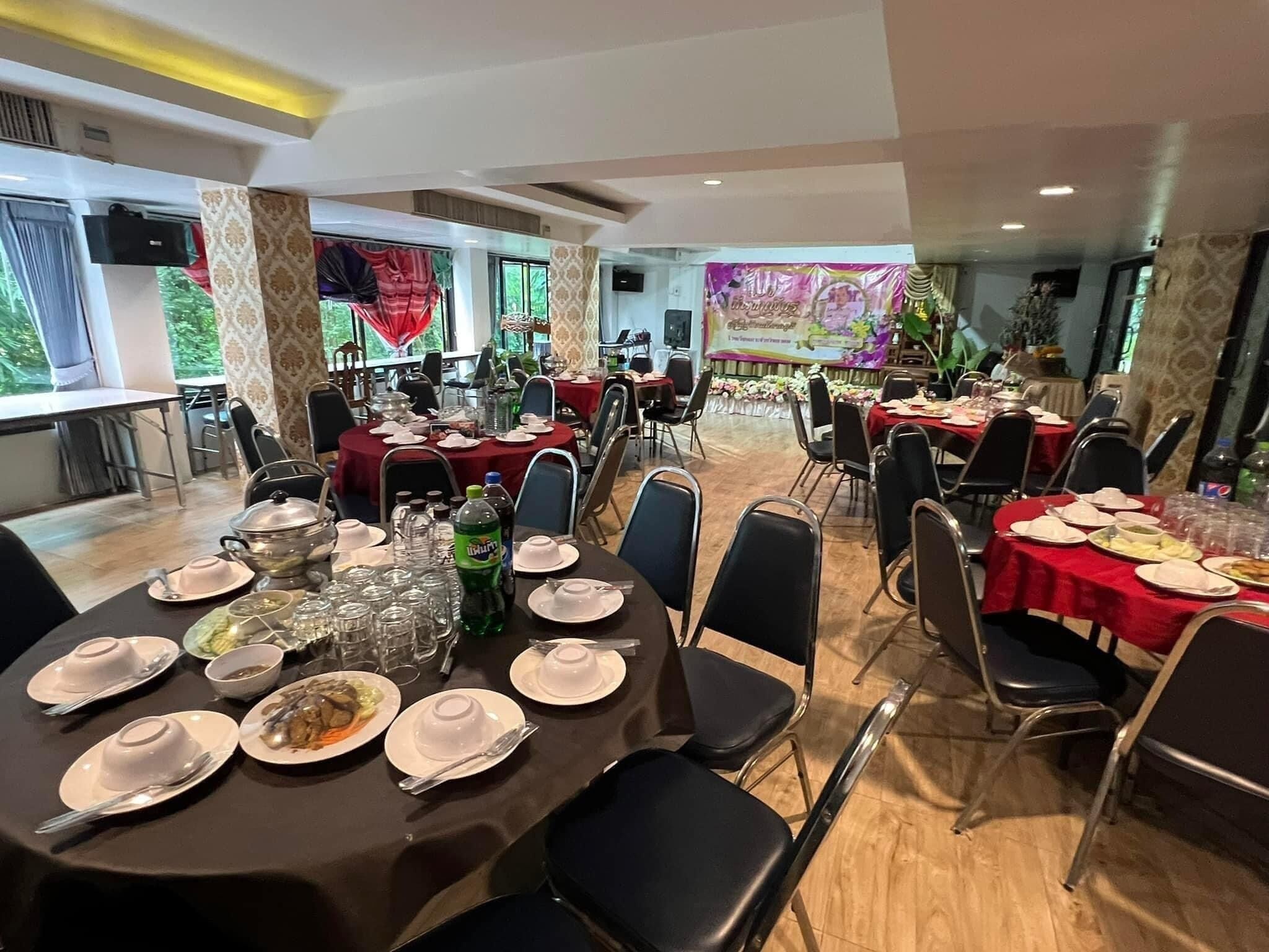 Un salón de banquetes con mesas redondas dispuestas para el servicio de comidas, equipado con platos, vasos y cubiertos.