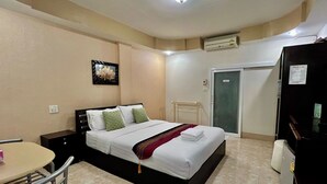 Ein Hotelzimmer mit einem Bett, einem Schreibtisch, einem Stuhl, einem Kleiderschrank und einer Tür.