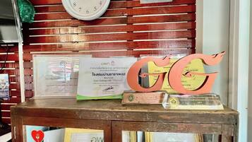 Una mesa de exhibición de madera con diplomas, un reloj y un letrero decorativo con las iniciales 'GG'.