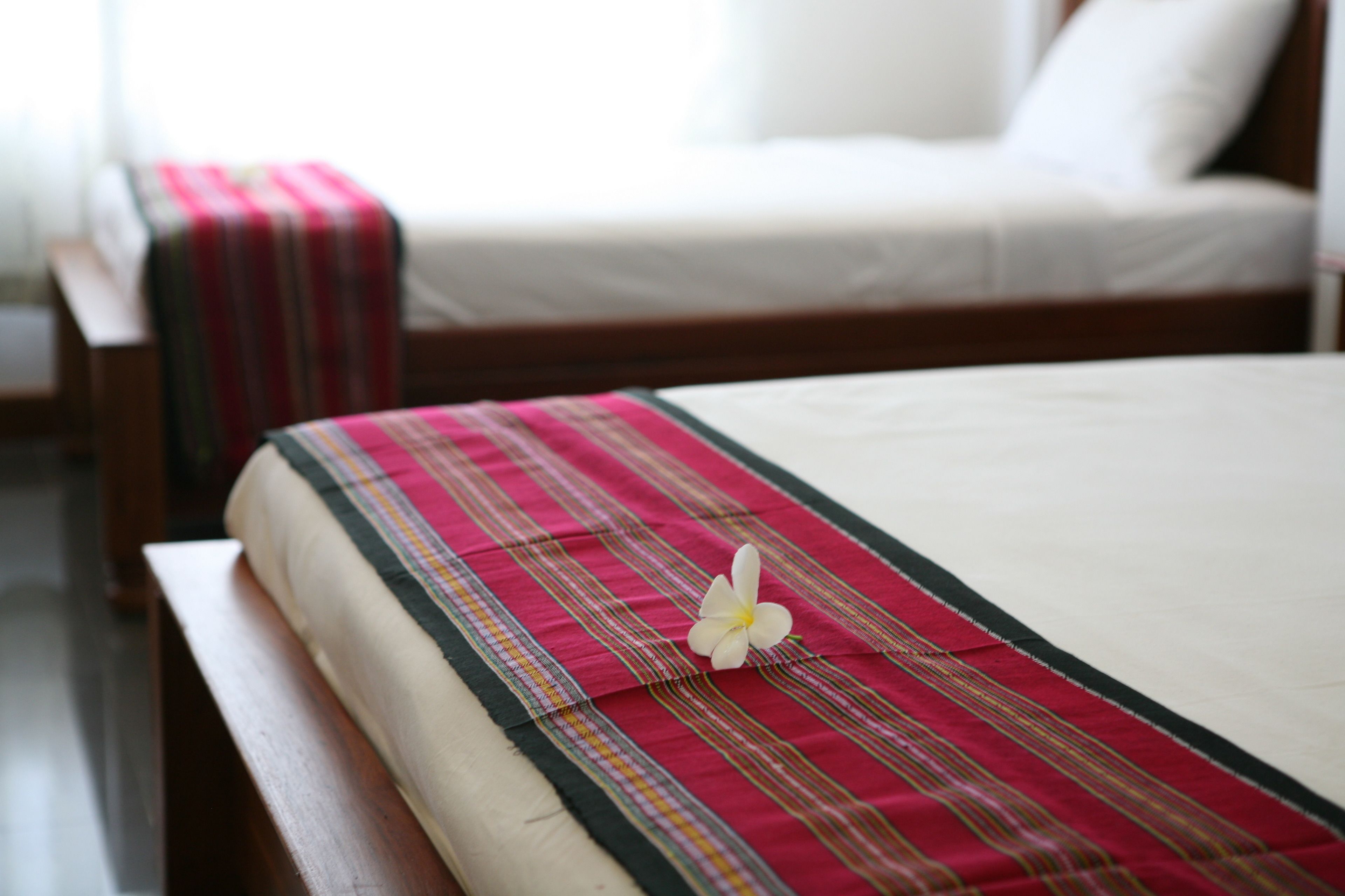 Ein Bett mit einer rot-weiß gestreiften Tagesdecke und einer weißen Blume.