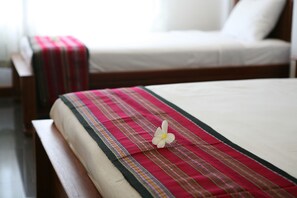 Un letto con una coperta a righe rosse e bianche e un fiore bianco.