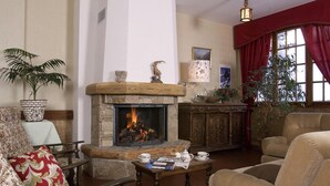 A cozy living room with a stone fireplace, a large window with red curtains, and a comfortable seating area with armchairs and a sofa. - Les Agneaux (Villar-d'Arene)