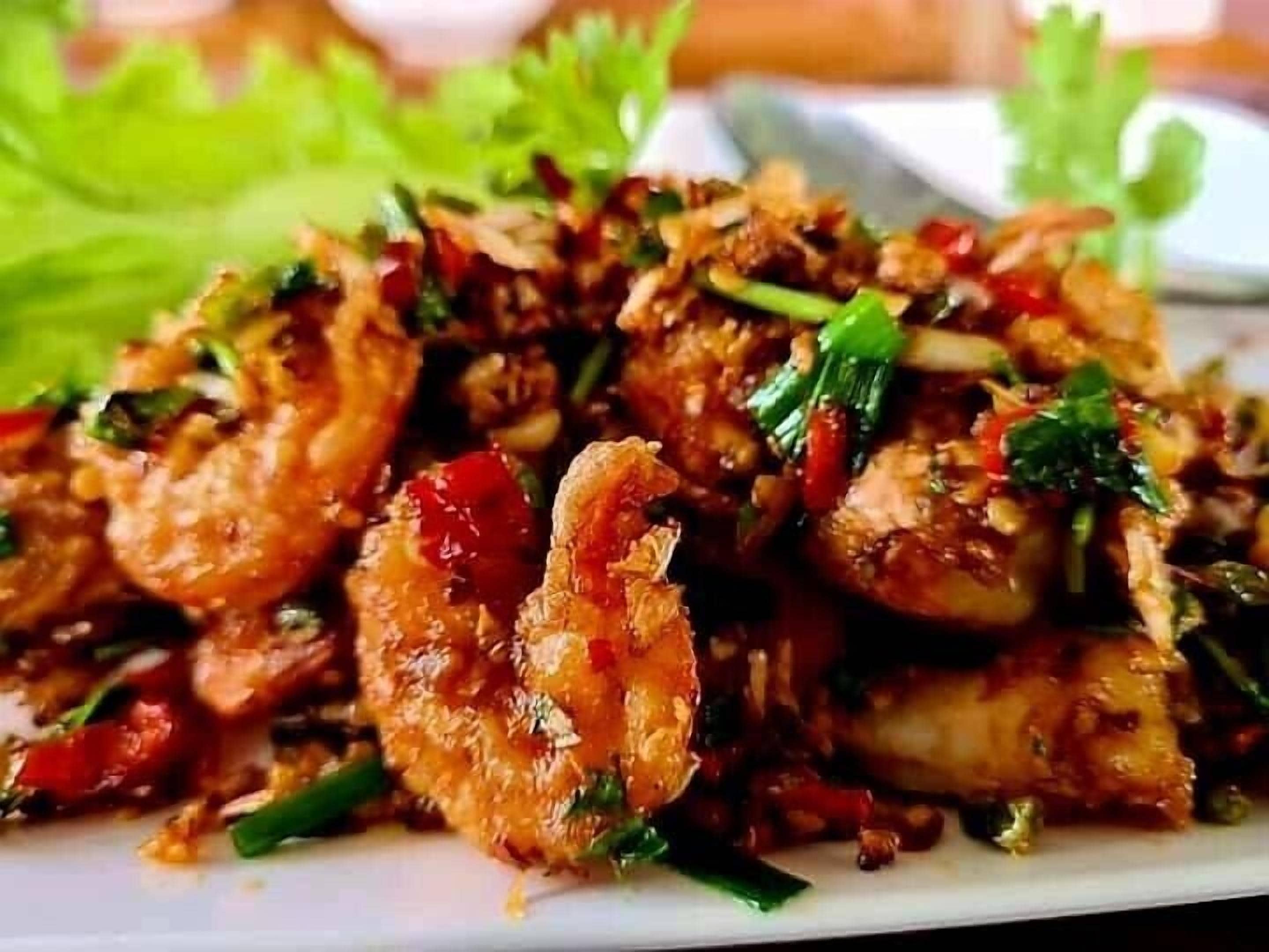 A plate of fried shrimp with vegetables and herbs.