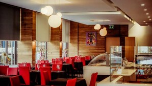 Un intérieur de restaurant moderne avec des chaises rouges, des tables rondes et des luminaires sphériques suspendus.