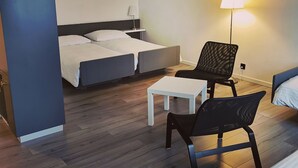 Une chambre d’hôtel moderne équipée d’un lit, d’un bureau, d’une chaise et d’une lampe.