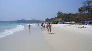 A beach with people walking and swimming, umbrellas, and beach chairs. - Rayong Rental Pool Villas (Klaeng)