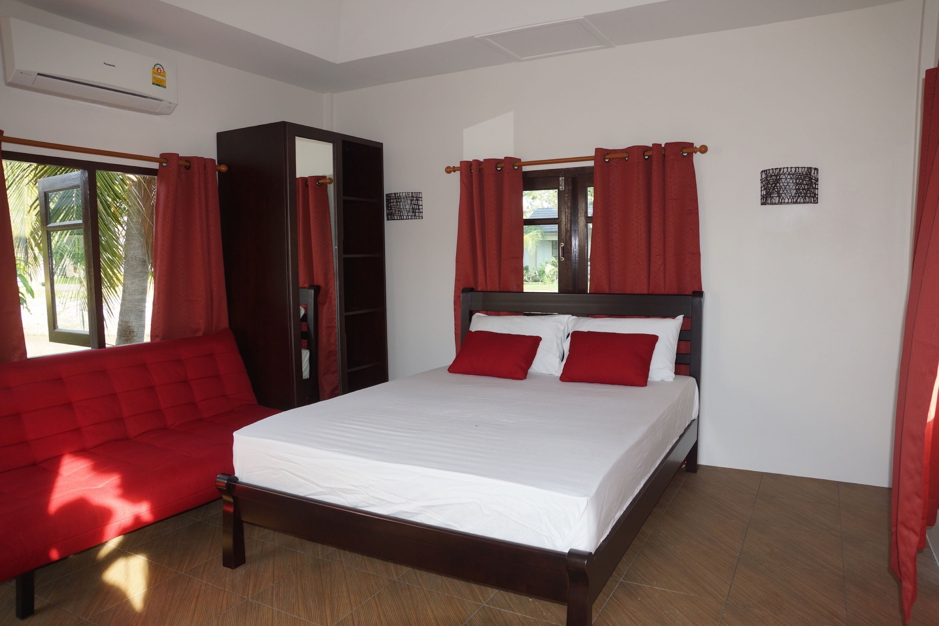 A bedroom with a bed, a wardrobe, and a sofa.