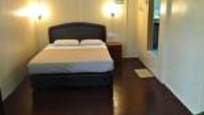 Une chambre d’hôtel avec un lit simple, des tables de chevet et des lampes fixées au mur.
