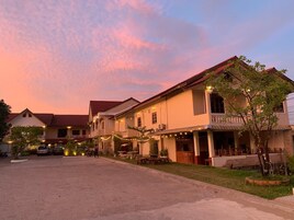 A two-story building with a red-tiled roof, multiple balconies, and string lights.