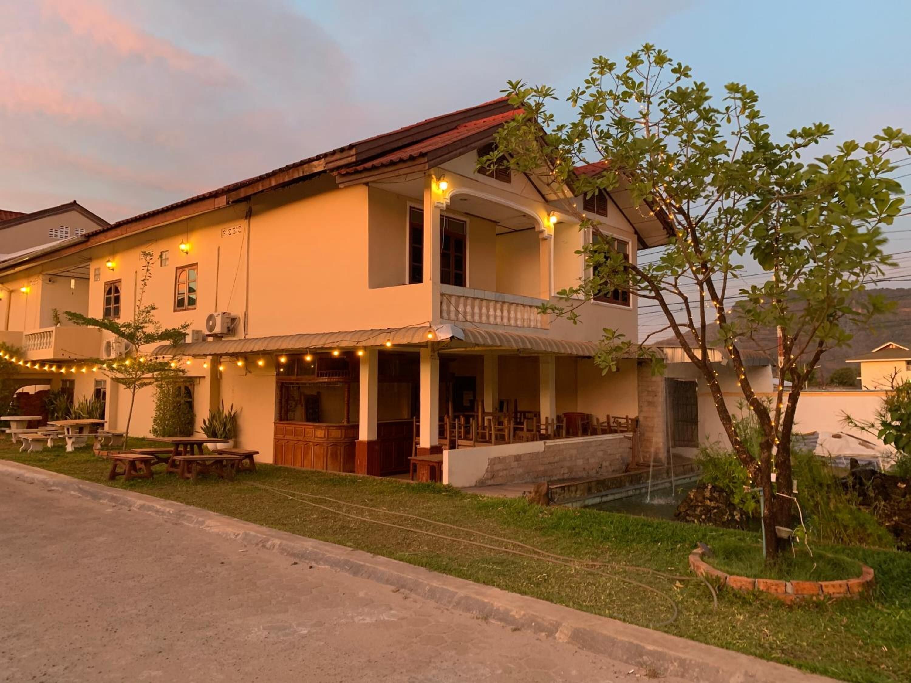 A two-story building with a balcony, outdoor seating, and string lights.