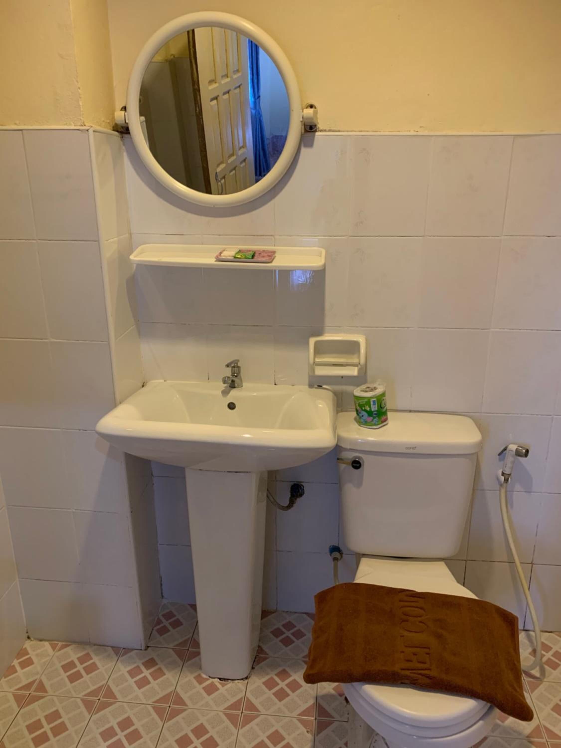 A bathroom with a white sink, toilet, and a towel on the floor.