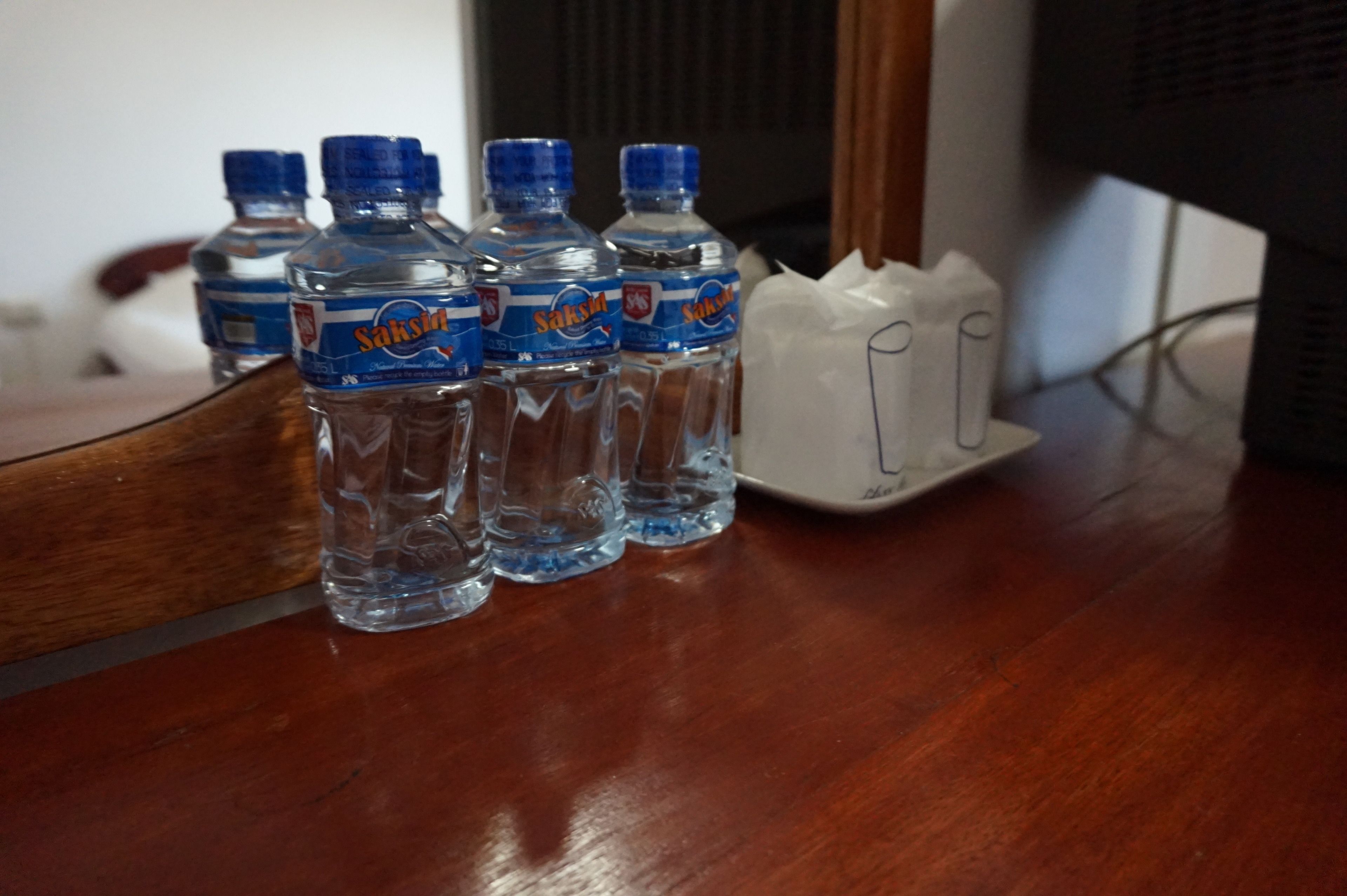 Cuatro botellas de agua y un cargador blanco sobre una mesa de madera.