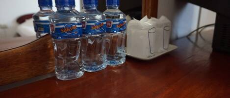 Four water bottles and a white charger on a wooden table.