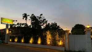 L’entrée d’un hôtel, avec un panneau indicateur, un chemin bien éclairé et une entrée fermée par un portail.
