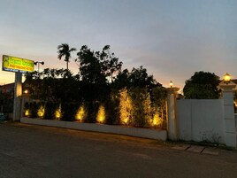 A hotel entrance with a signboard, a well-lit pathway, and a gated entrance.